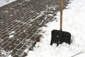 Black plastic snow shovel and pavement. Seasonal background.